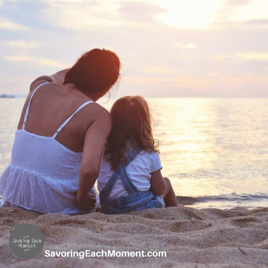 Mother sitting with daughter beside the water, encouraged by Bible verses about a mother's love