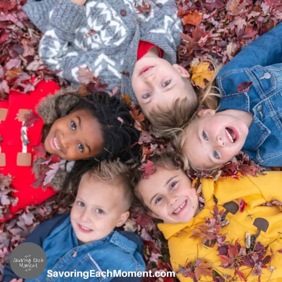 Kids laying in a pile of leaves in the fall