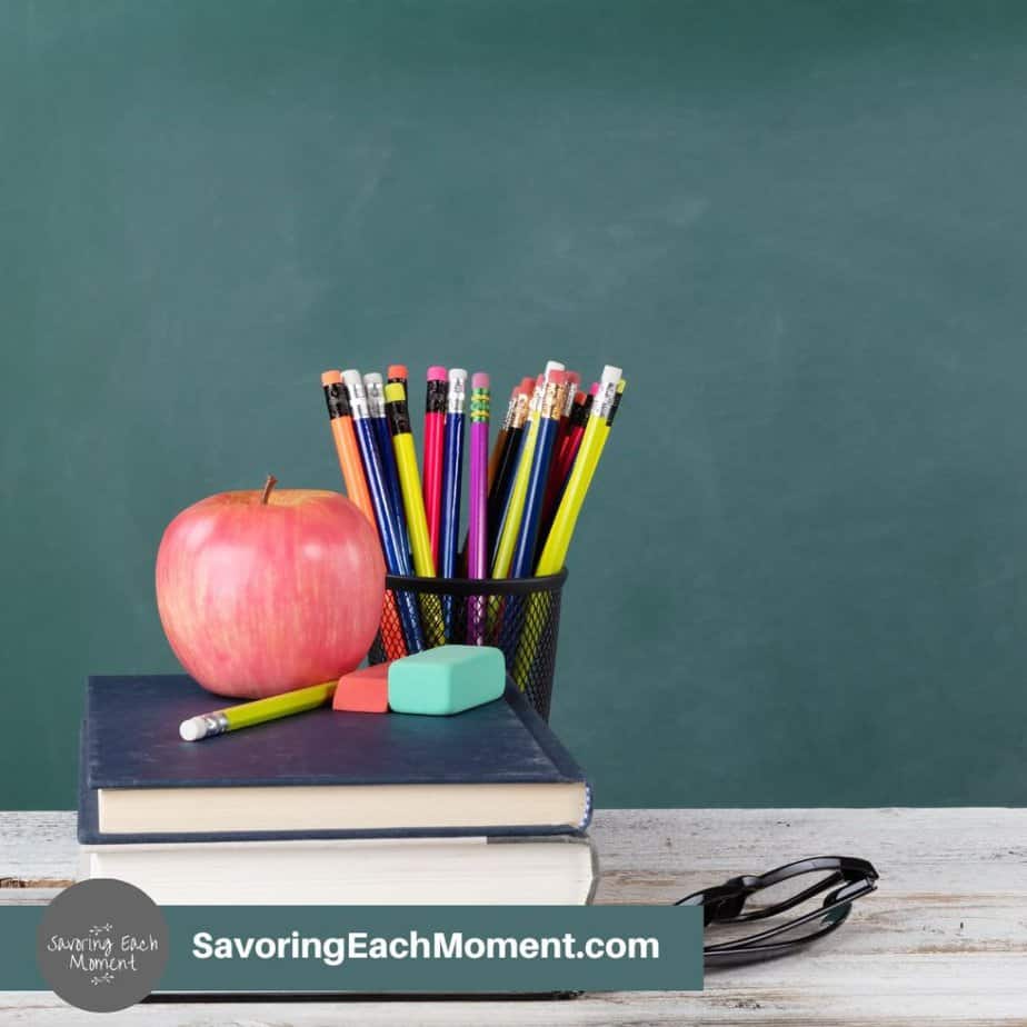green chalkboard behind a desk with pencils, books, and an apple. Bible verses for teachers.