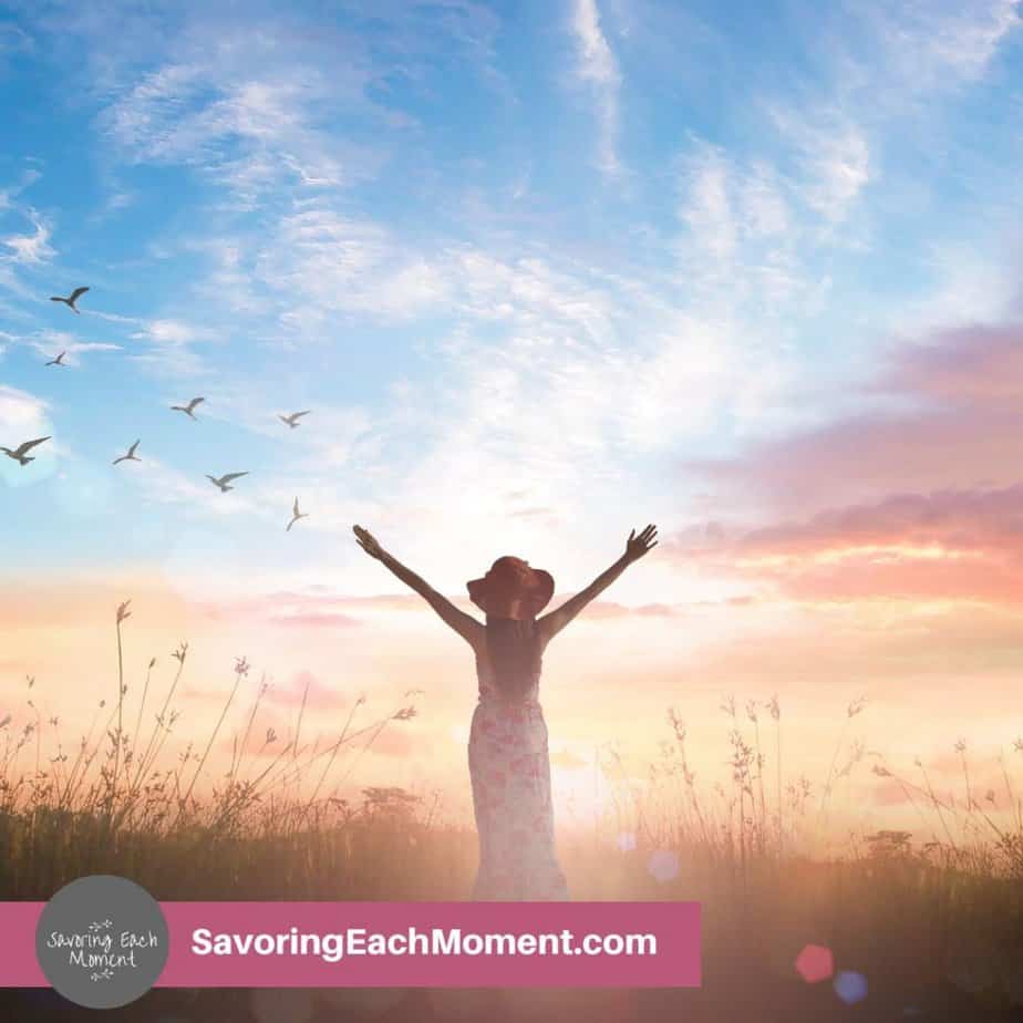 woman in a field with arms raised to the sky