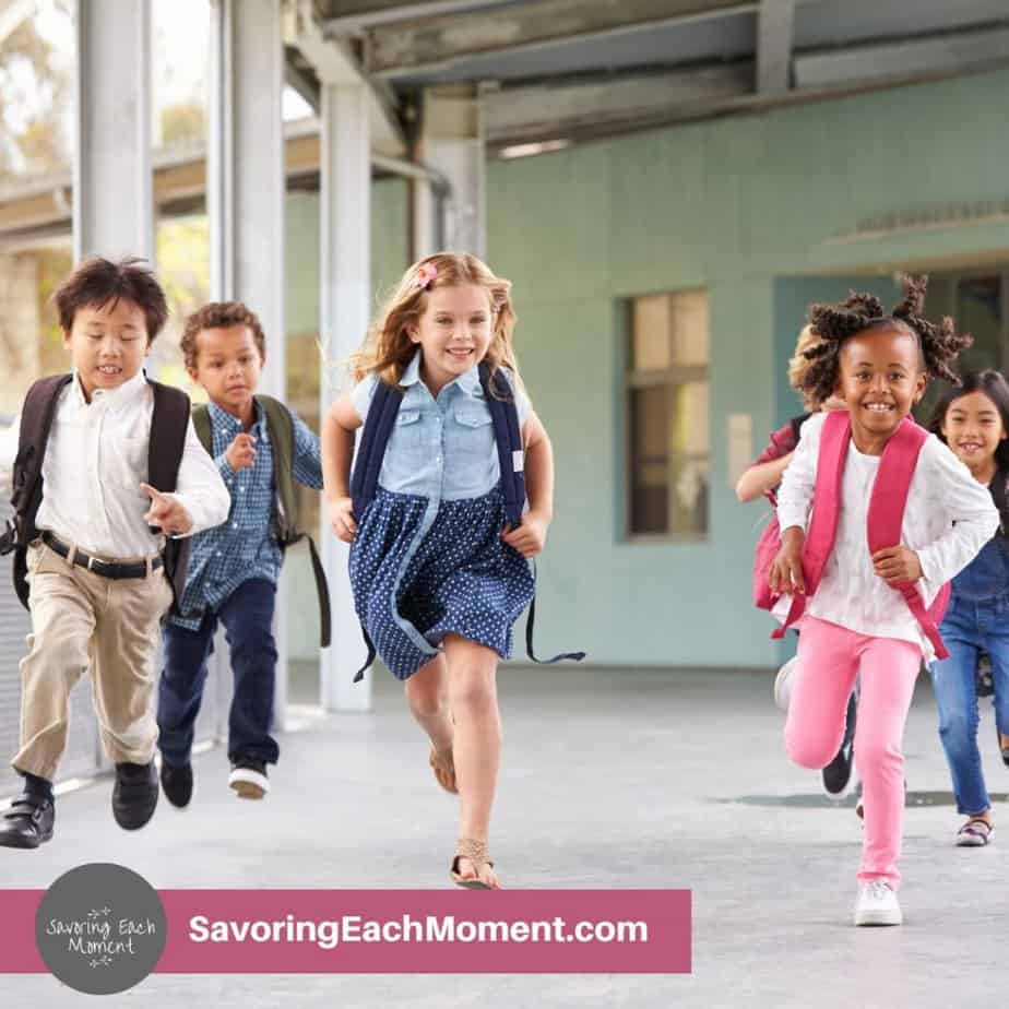 young children running toward school carrying backbacks